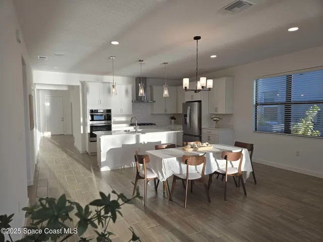 a dining room with furniture a chandelier and kitchen view