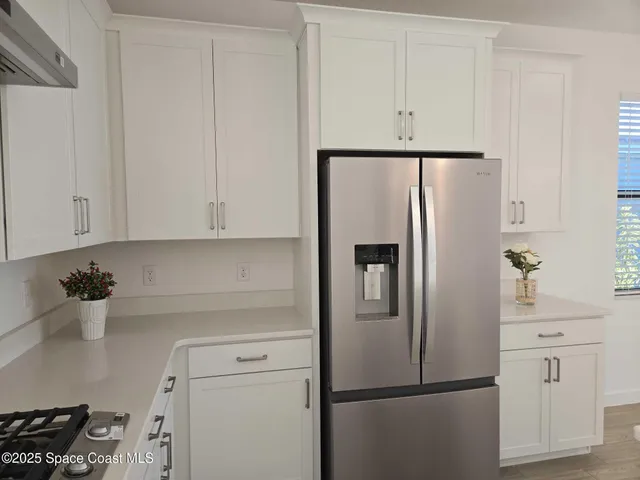 a kitchen with refrigerator and white cabinets