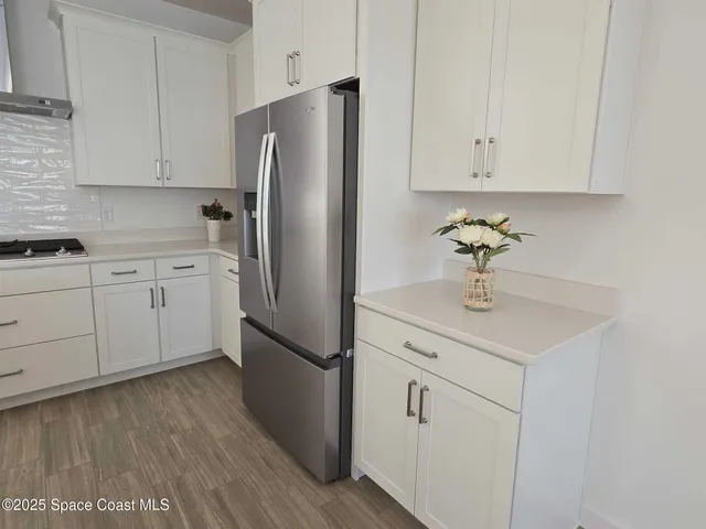 a kitchen with stainless steel appliances a sink cabinets and wooden floor