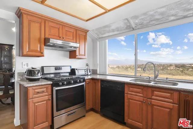 a kitchen with stainless steel appliances granite countertop a stove a sink and dishwasher with wooden cabinets