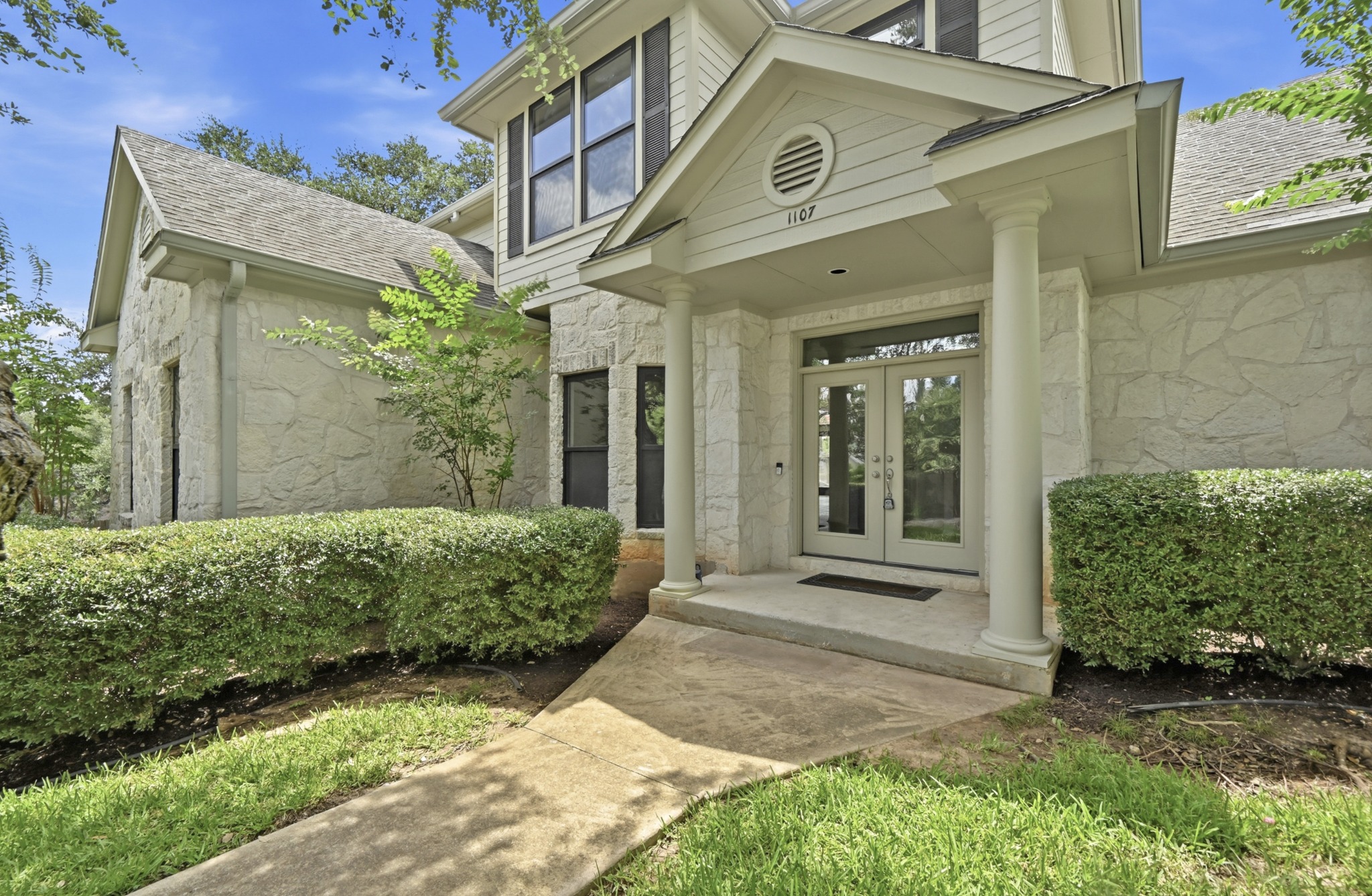 1107 Bowie Road Austin, TX 78733 - Photo 4 of 40 A welcoming front entrance featuring stately columns and a combination of stone and siding.