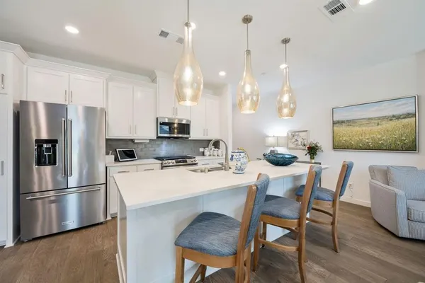 a kitchen with stainless steel appliances a dining table chairs and wooden floor