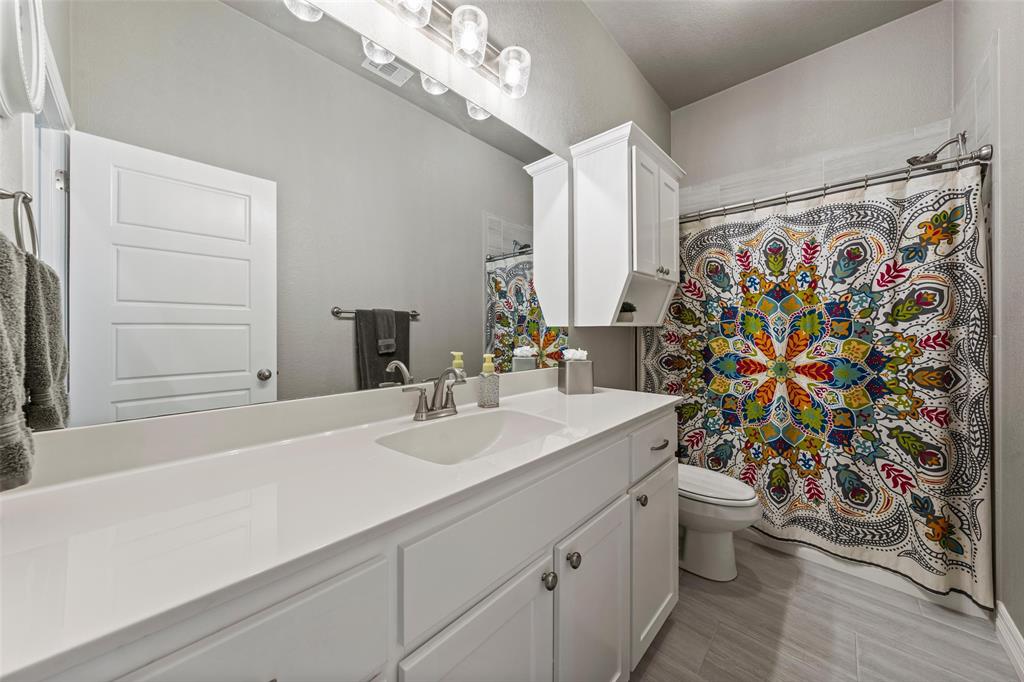 828 Agile Street Hewitt, TX 76643 - Photo 15 of 30 a bathroom with a sink a toilet and shower curtain