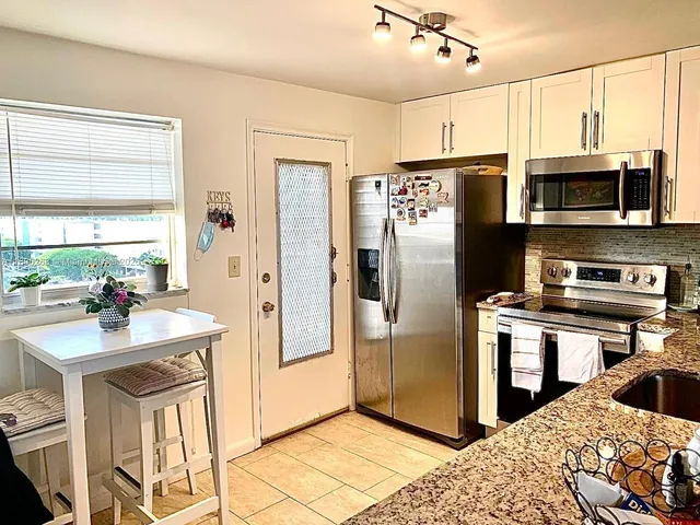 a kitchen with stainless steel appliances granite countertop a refrigerator a stove and a sink