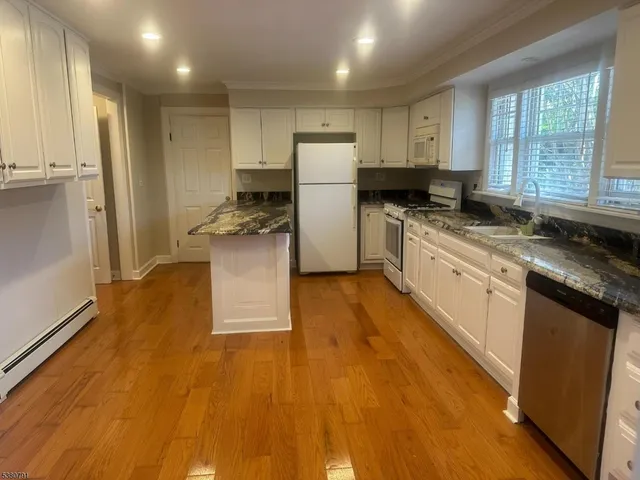 a kitchen with a sink wooden floor and stainless steel appliances