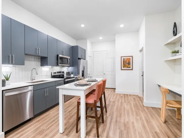 a kitchen with stainless steel appliances a sink a stove a refrigerator cabinets and wooden floor