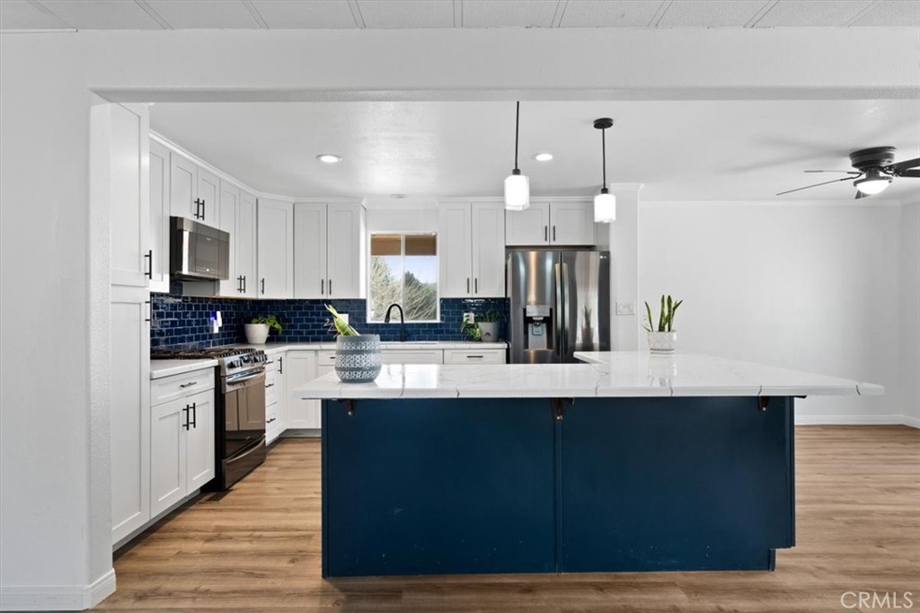 a kitchen with kitchen island granite countertop a sink cabinets and stainless steel appliances