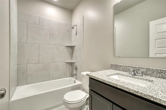 a bathroom with a granite countertop bathtub shower sink vanity and toilet