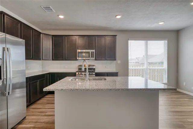 a kitchen with kitchen island granite countertop a sink window and refrigerator