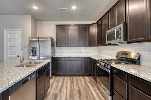 a kitchen with stainless steel appliances granite countertop a sink stove and refrigerator
