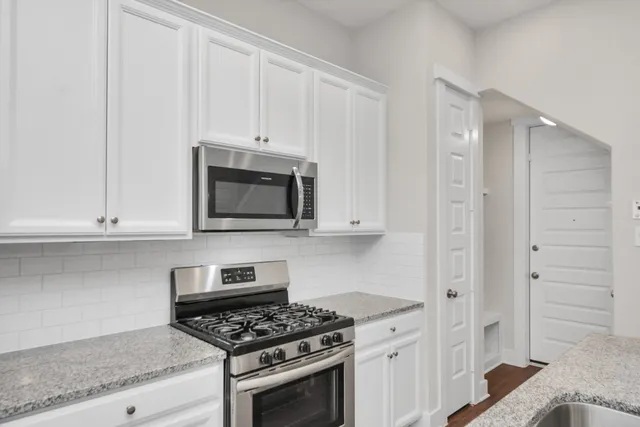 a kitchen with white cabinets and stainless steel appliances