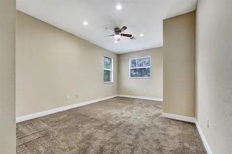 an empty room with windows and ceiling fan