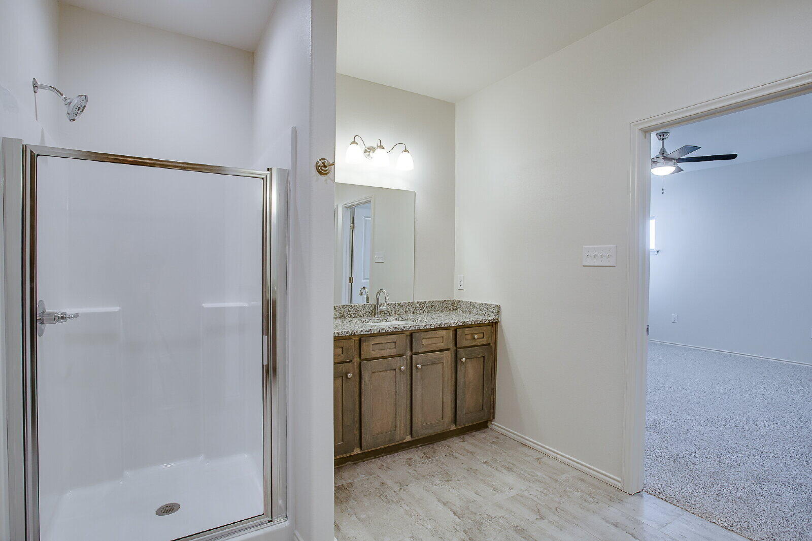 5520 121st Street, Unit B Lubbock, TX 79424 - Photo 11 of 17 a spacious bathroom with a granite countertop sink a mirror and a shower