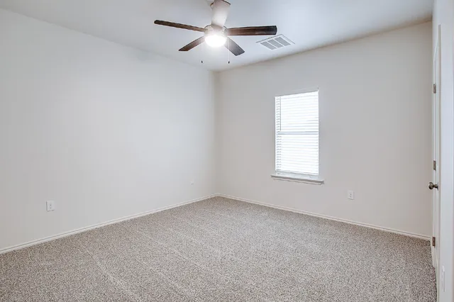 an empty room with a window and a ceiling fan