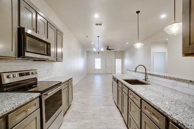 a kitchen with stainless steel appliances granite countertop a sink a stove and oven