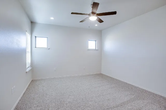 an empty room with a window and a fan