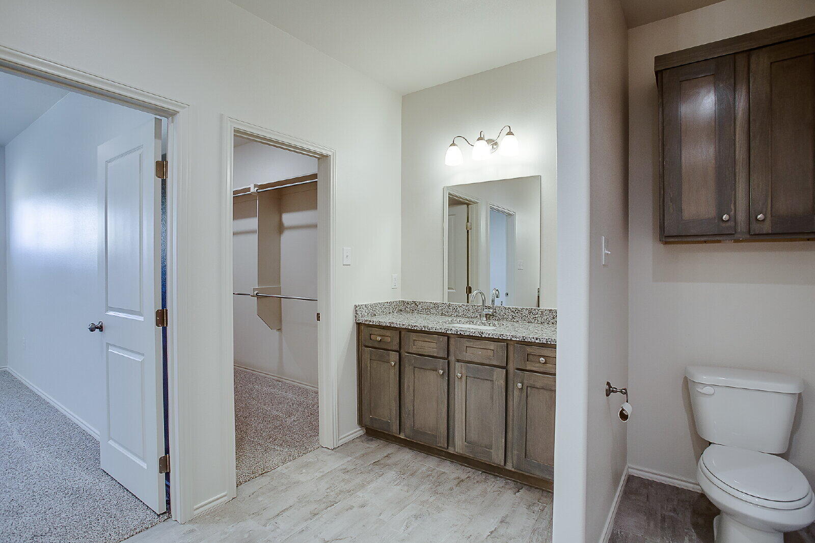 5520 121st Street, Unit B Lubbock, TX 79424 - Photo 10 of 17 a bathroom with a granite countertop sink a toilet and a mirror