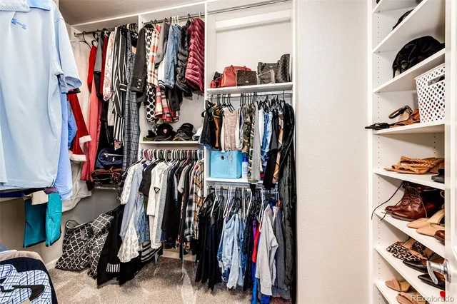 a view of walk in closet with clothes and shoes