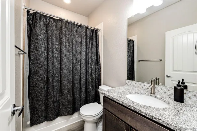 a bathroom with a granite countertop sink toilet and shower