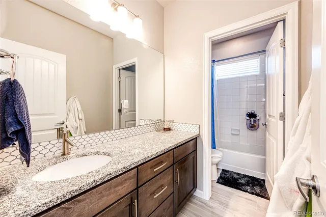 a bathroom with a granite countertop sink a mirror and a shower