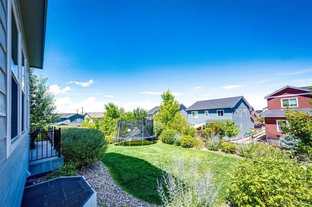 a view of a house with a big yard plants and large tree