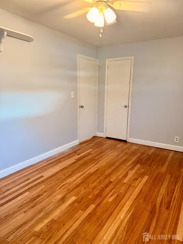 an empty room with wooden floor and fan