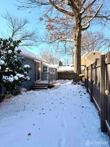 a backyard of a house with wooden fence and large trees