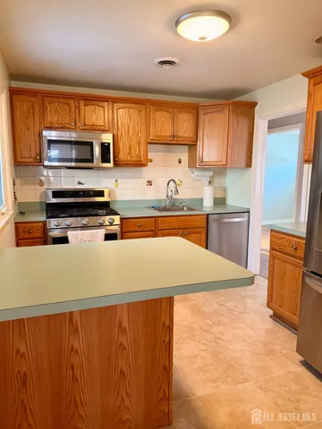 a kitchen with stainless steel appliances a refrigerator a sink a stove top oven and a refrigerator