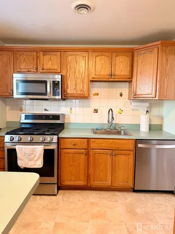 a kitchen with stainless steel appliances granite countertop a stove a sink and a microwave