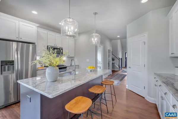 a kitchen with stainless steel appliances granite countertop a table chairs and a refrigerator