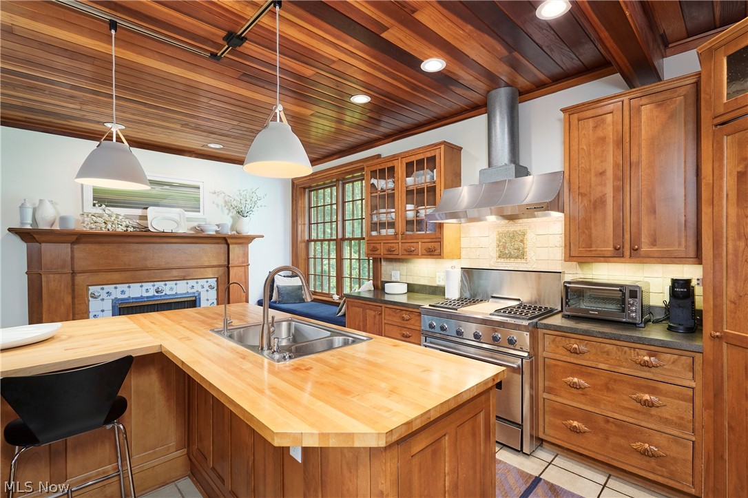 5046 Alger Road Richfield, OH 44286 - Photo 23 of 49 Kitchen featuring a wood plank ceiling, light wood countertops, stainless steel appliances, and a decorative fireplace with blue and white tile