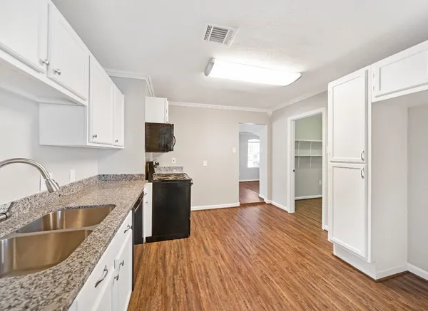 a kitchen with granite countertop a refrigerator stove top oven and sink