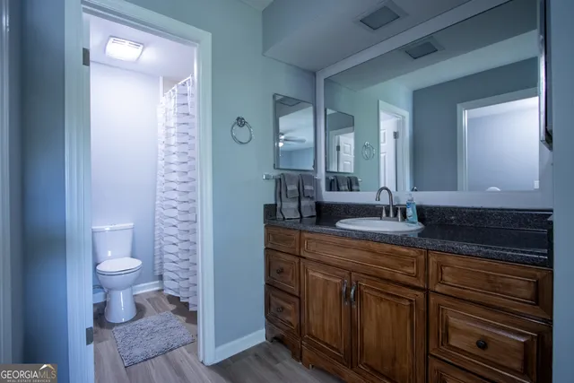 a spacious bathroom with a granite countertop sink a toilet and a mirror