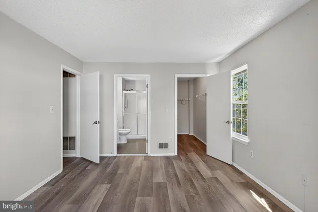 a view of an empty room with window and wooden floor