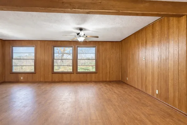 a view of an empty room with a window and wooden floor