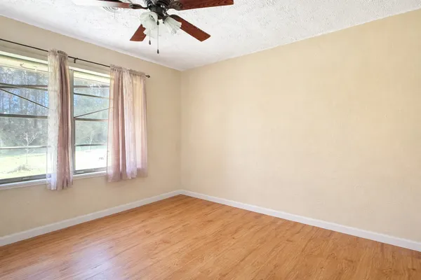 an empty room with a window and a ceiling fan