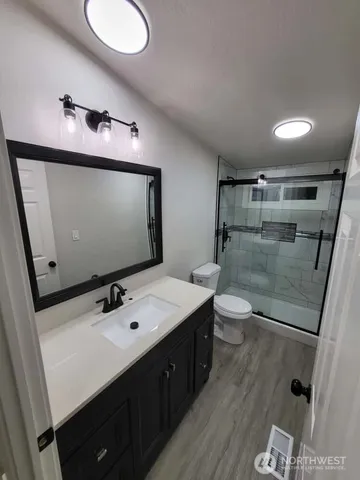a bathroom with a sink a toilet a mirror and shower