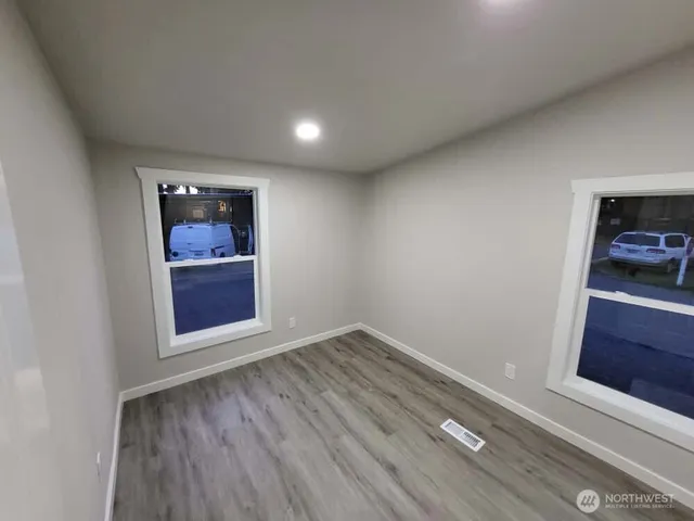 an empty room with wooden floor cabinet and window