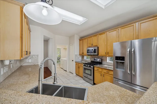 a kitchen with stainless steel appliances granite countertop a sink a stove counter space and cabinets
