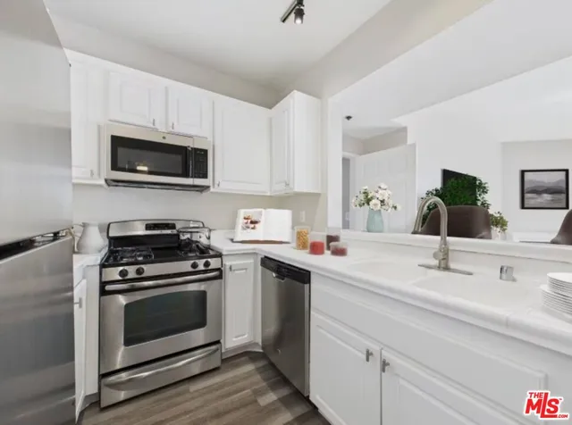 a kitchen with white cabinets and stainless steel appliances