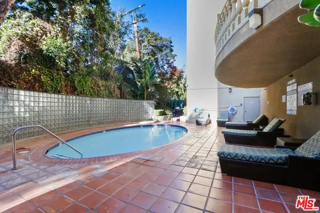 a view of swimming pool with seating space and trees in the background