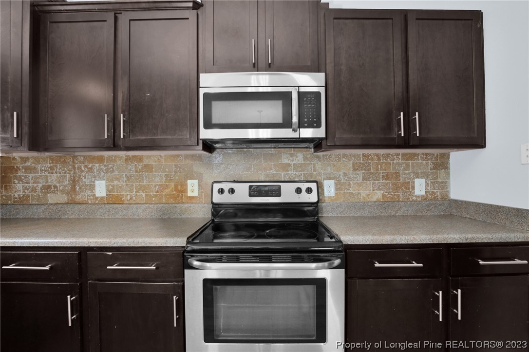 159 Boswell Street Raeford, NC 28376 - Photo 14 of 34 a kitchen with stainless steel appliances wooden cabinets and a stove top oven