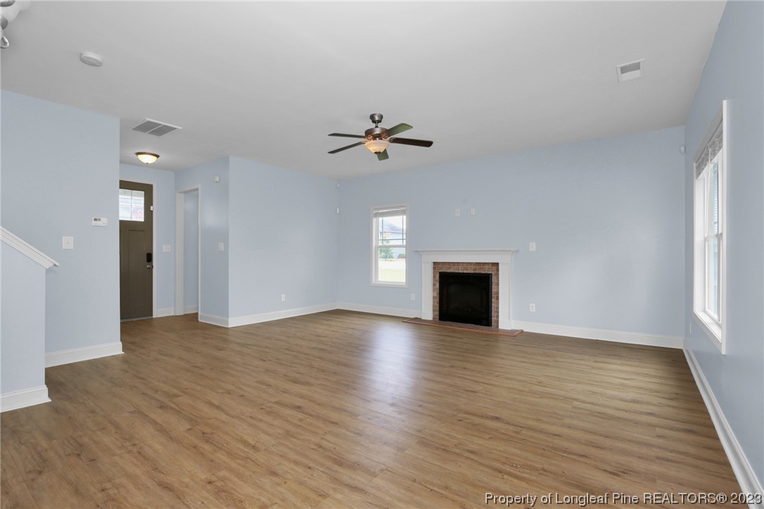 159 Boswell Street Raeford, NC 28376 - Photo 7 of 34 an empty room with wooden floor ceiling fan and windows