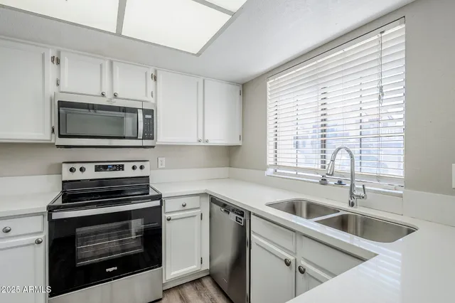 a kitchen with white cabinets a sink and appliances