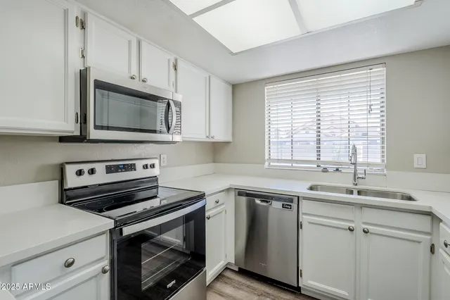 a kitchen with cabinets appliances a sink and a window