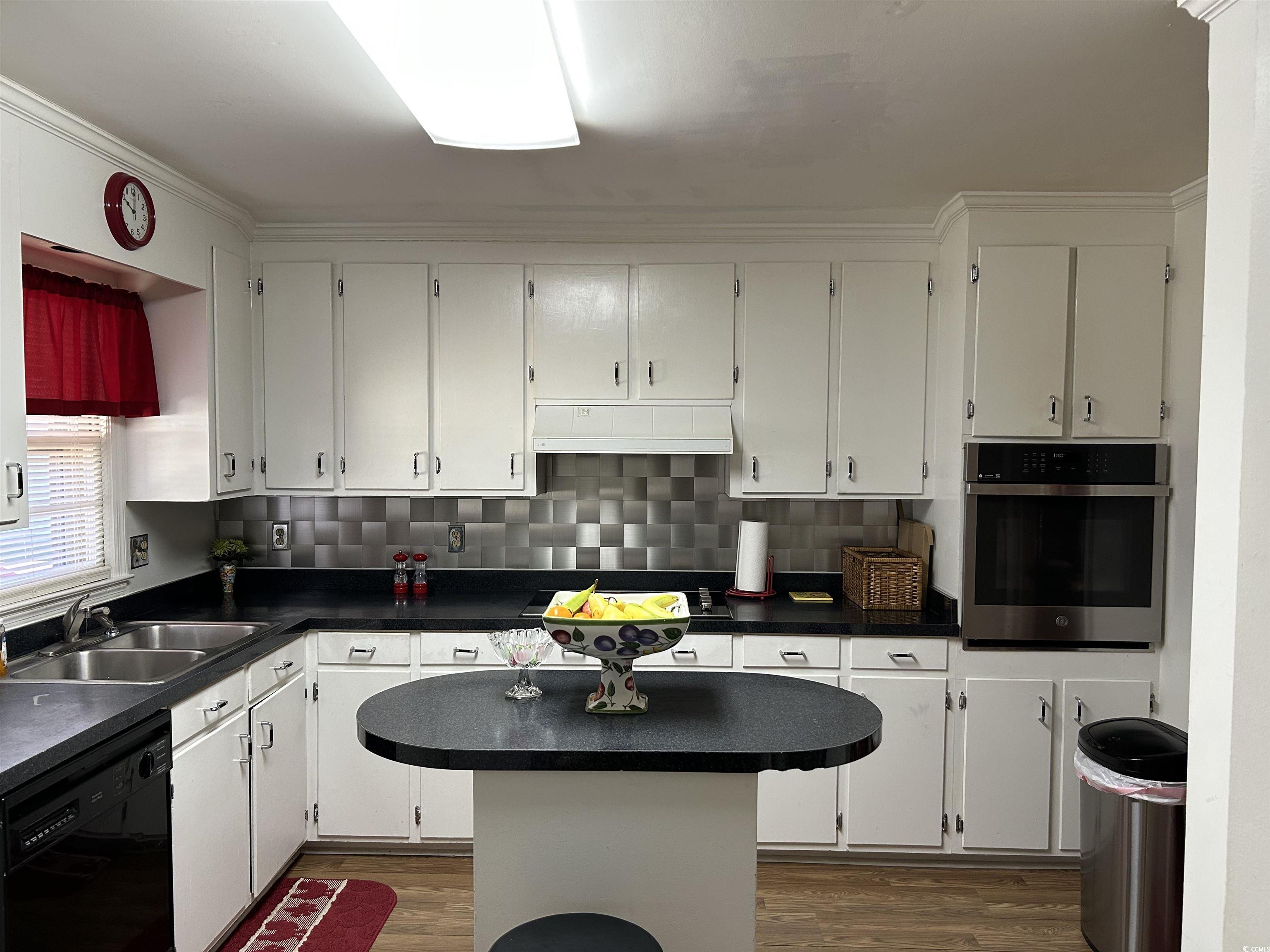 1411 East Harrison Street Dillon, SC 29536 - Photo 13 of 40 Kitchen with dark countertops, oven, dark wood finished floors, black dishwasher, and backsplash