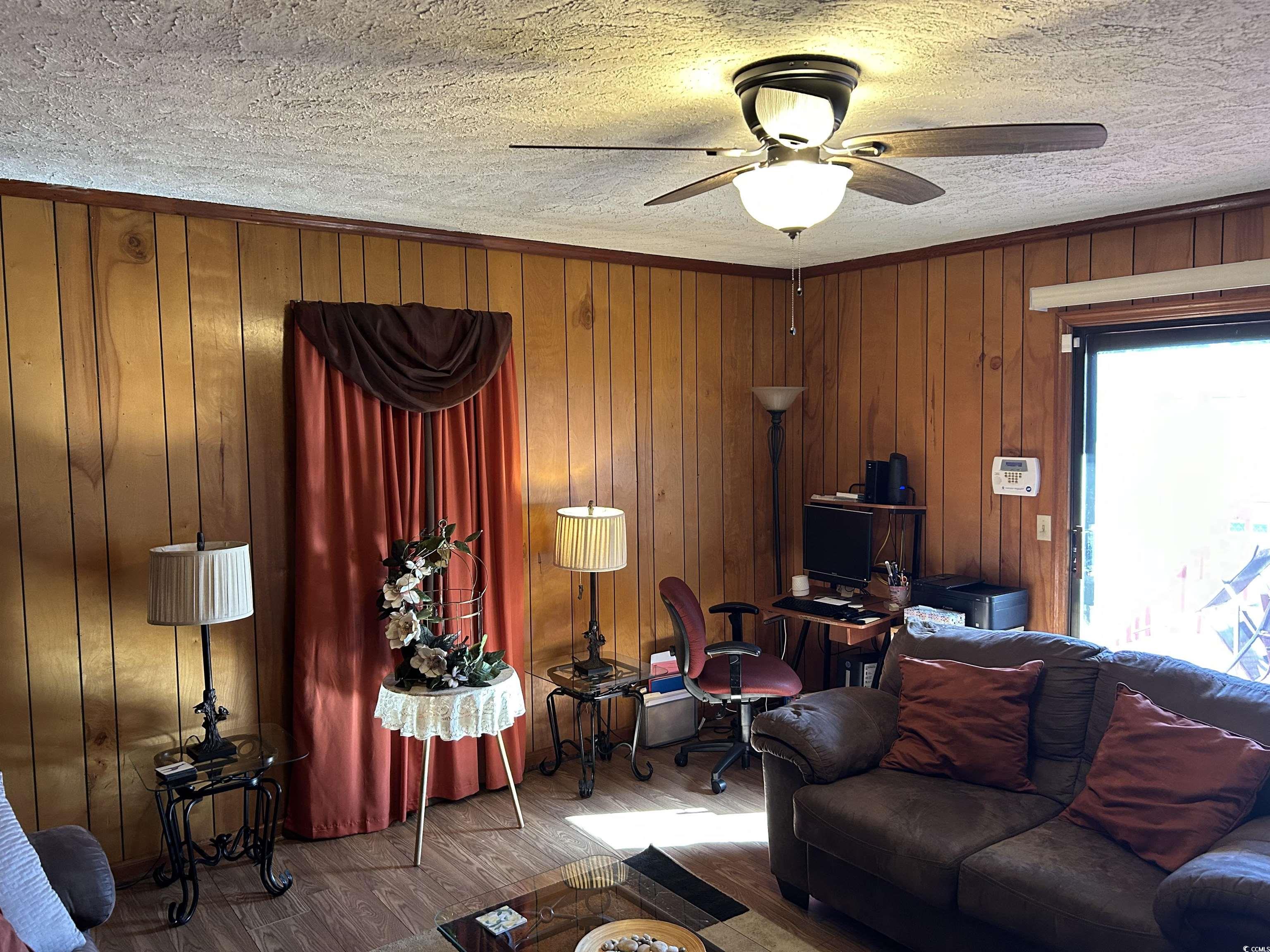 1411 East Harrison Street Dillon, SC 29536 - Photo 17 of 40 Living room featuring wood finished floors, wood walls, a textured ceiling, and ceiling fan