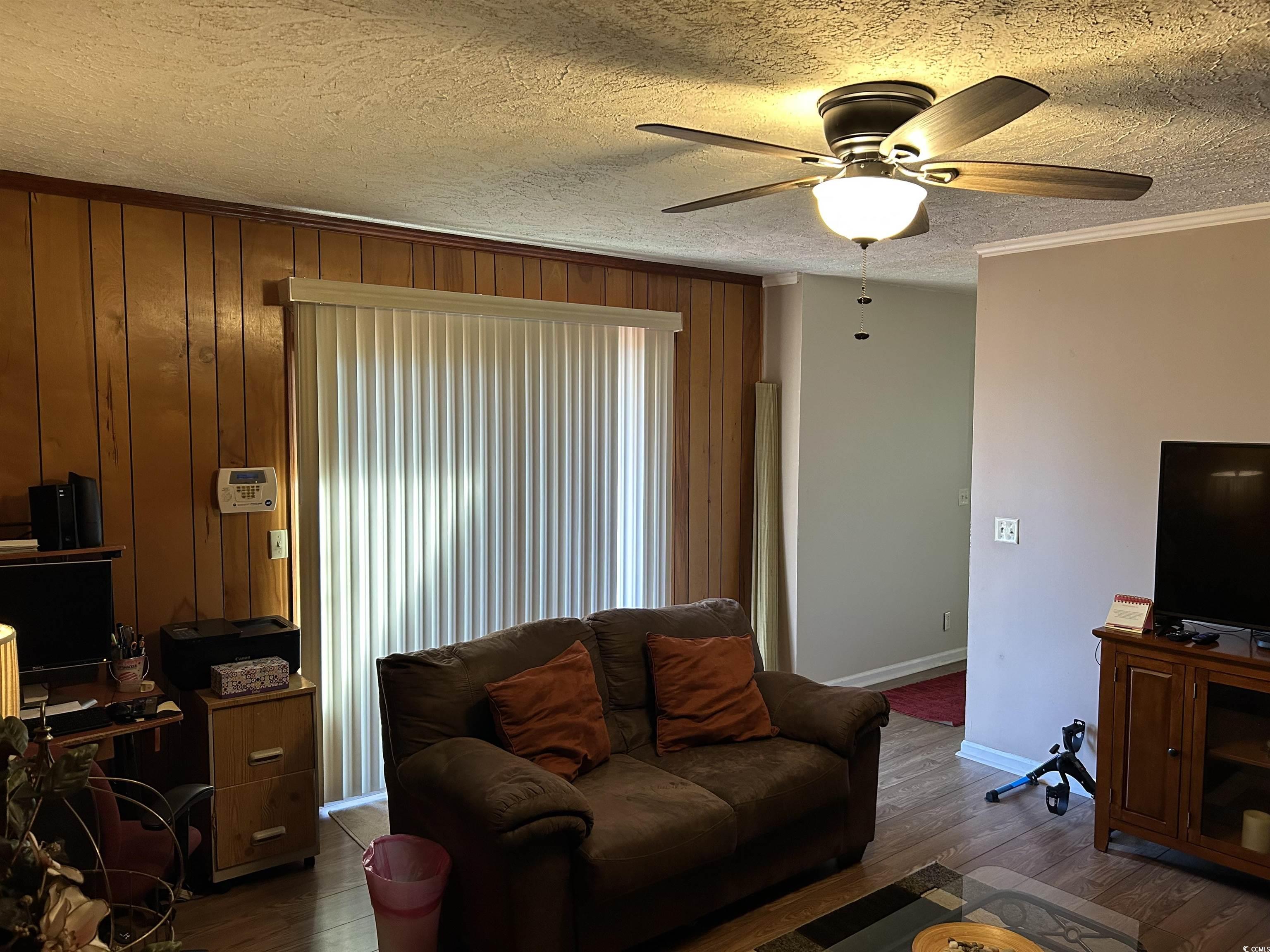 1411 East Harrison Street Dillon, SC 29536 - Photo 18 of 40 Living area featuring a textured ceiling, an office area, wood finished floors, a ceiling fan, and wooden walls