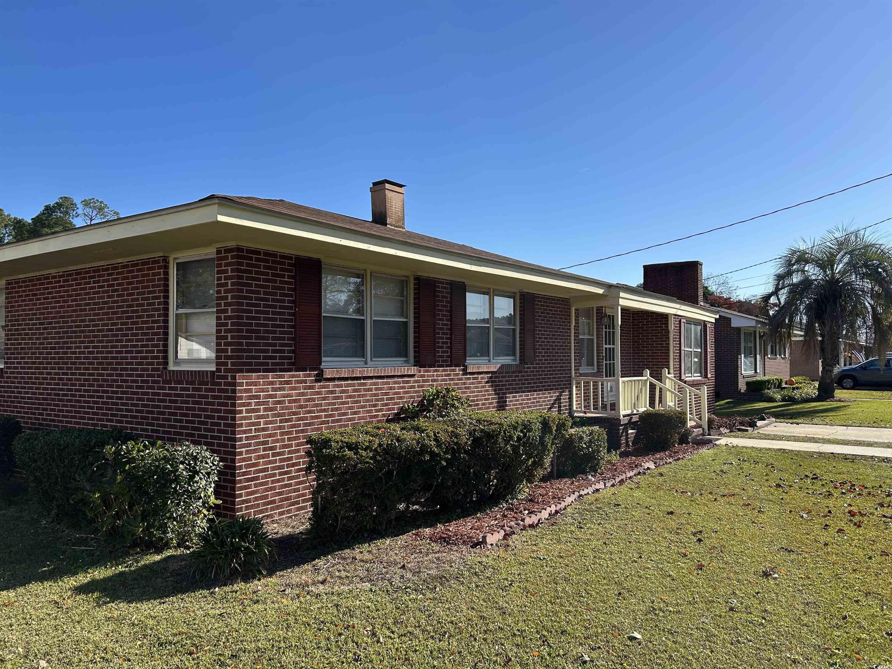 1411 East Harrison Street Dillon, SC 29536 - Photo 3 of 40 View of side of property featuring a chimney, a lawn, a porch, and brick siding