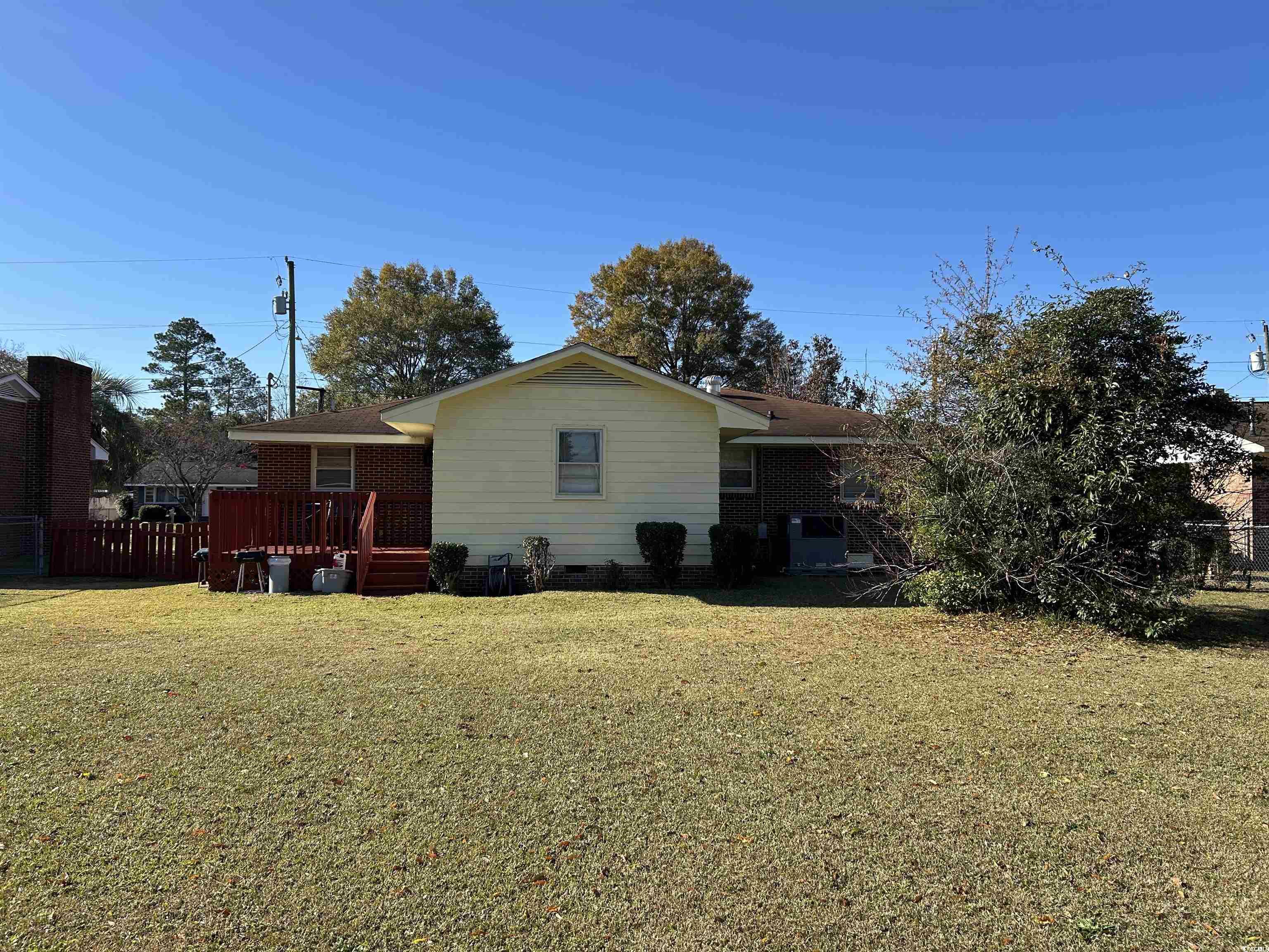 1411 East Harrison Street Dillon, SC 29536 - Photo 38 of 40 Rear view of property with a deck, a lawn, and brick siding